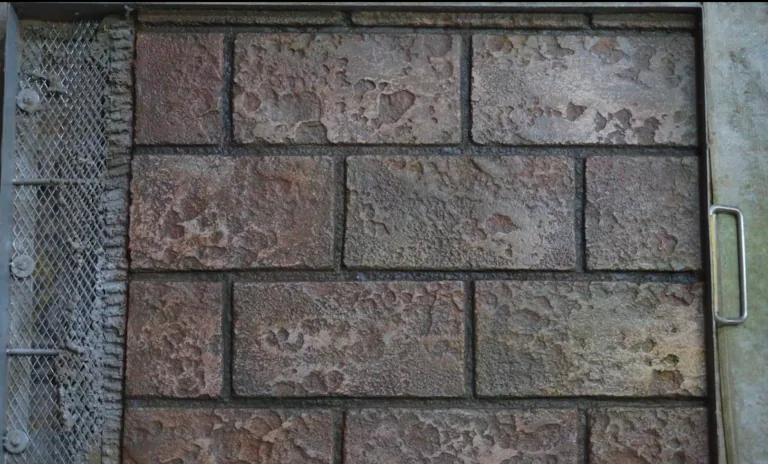 Rough, textured, aged bricks are laid in a wall with metal mesh and a handle visible.
