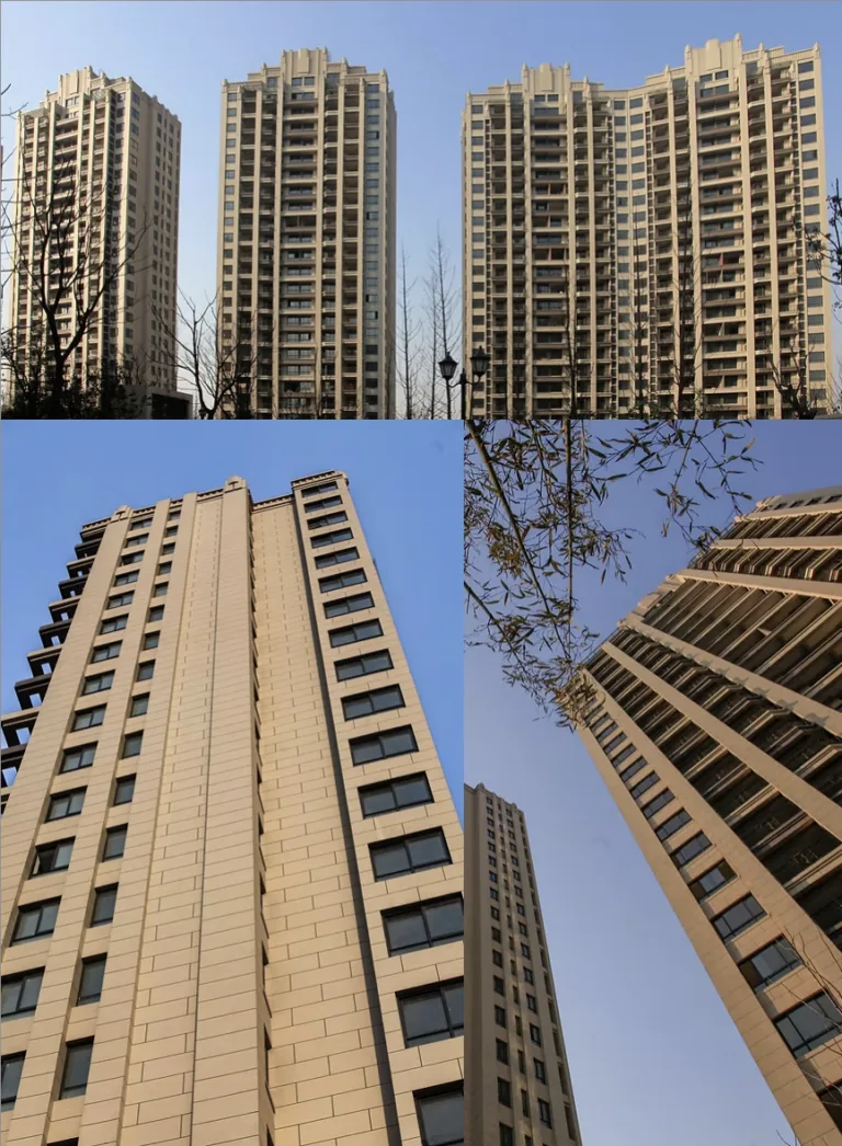 Modern apartment buildings with beige facades and many windows stand against a clear blue sky.